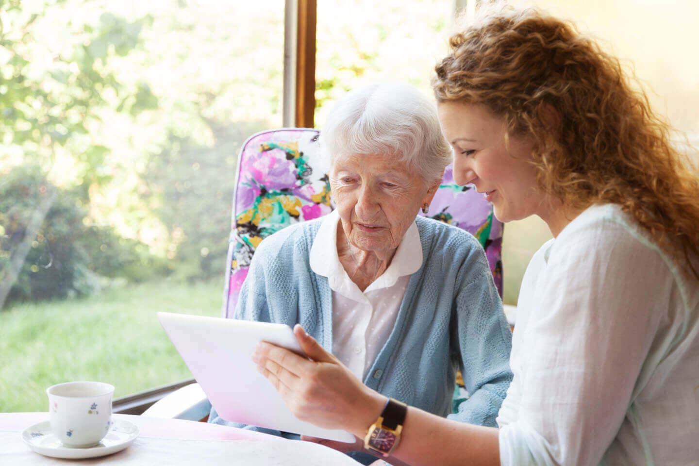Elderly women being supported in reading a document