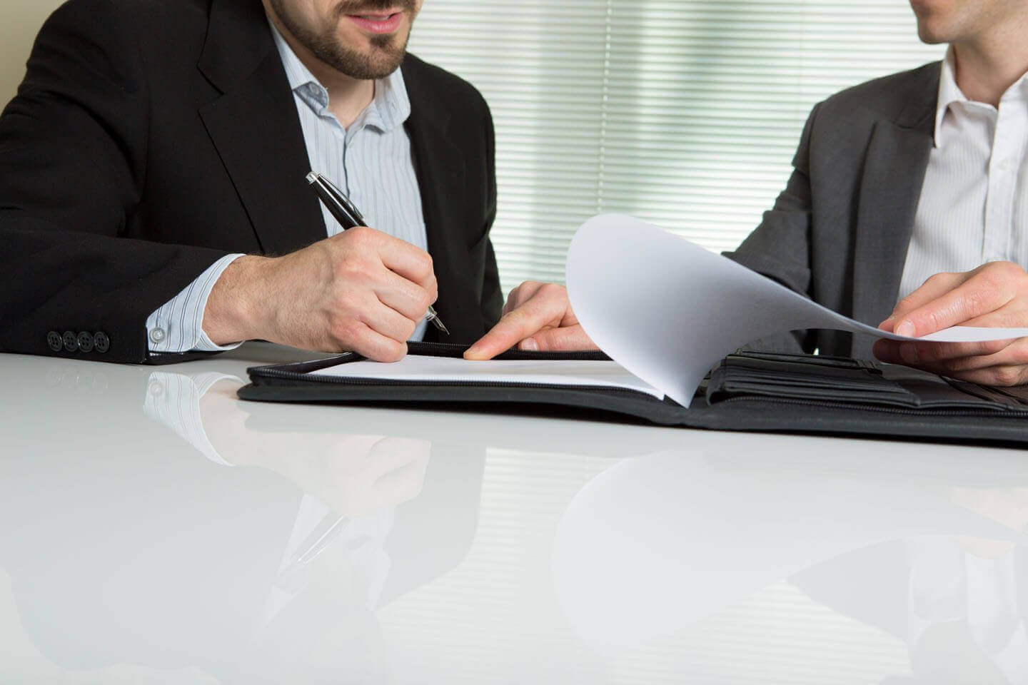 A man signing a contract under the advice of another