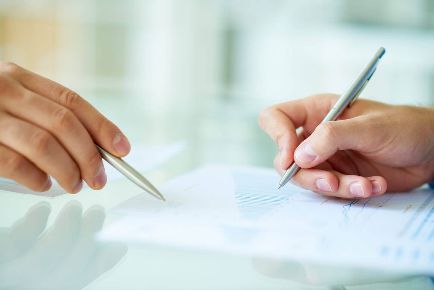 Two people point a various piece of information on a document