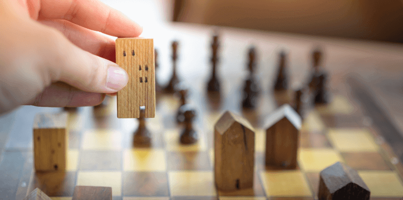 transfer of equity illustrated by a man playing chess with houses